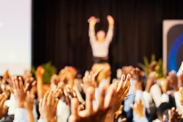 raised hands at a conference discussing membership surveys