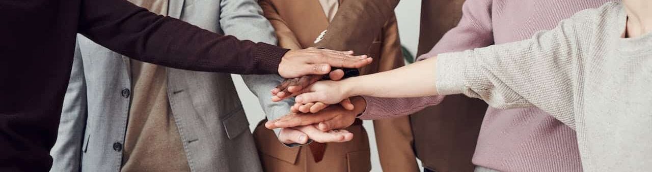 group of staff with hands in the middle of a circle, demonstrating organisational culture